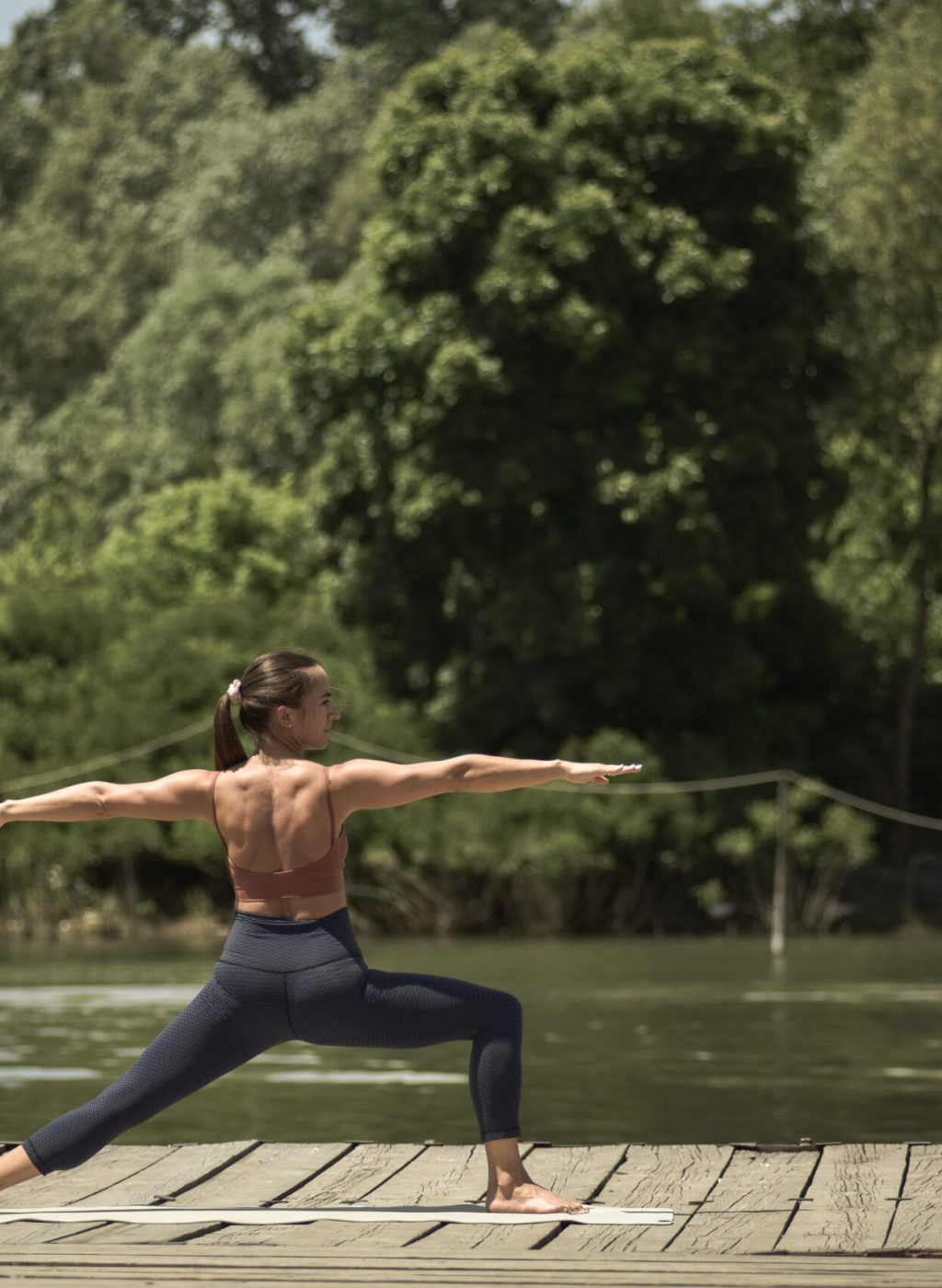 A young woman practicing yoga outdoors at the river